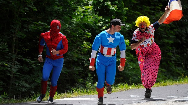 Fãs de ciclismo fantasiados de Homem-Aranha, Capitão América e um palhaço correm para ver a passagem dos ciclistas na 12ª estapa do Tour de France, no sul da França