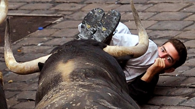 Jovem luta com touro durante festival São Firmino em Pamplona, Espanha