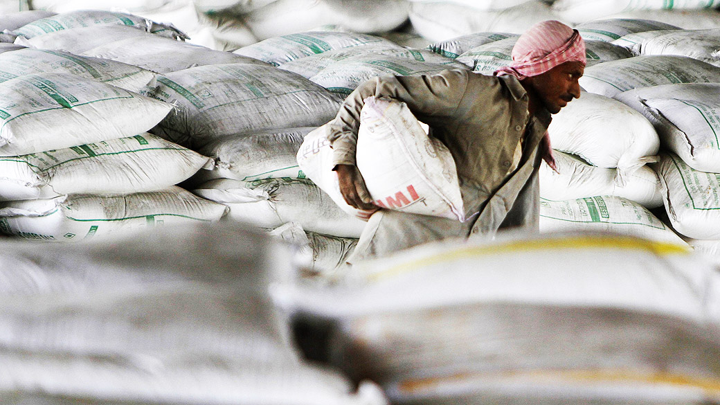 Trabalhador carrega um saco de cimento num caminhão, no pátio ferroviário de mercadorias na periferia da cidade ocidental indiana de Ahmedabad
