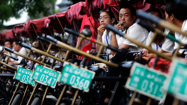 Puxadores de riquixá esperam por clientes no centro de Pequim, na China