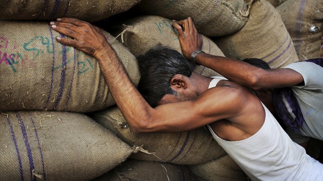 Trabalhadores indianos empurram sacas de tempero em um armazém no mercado de especiarias de Nova Délhi, na Índia
