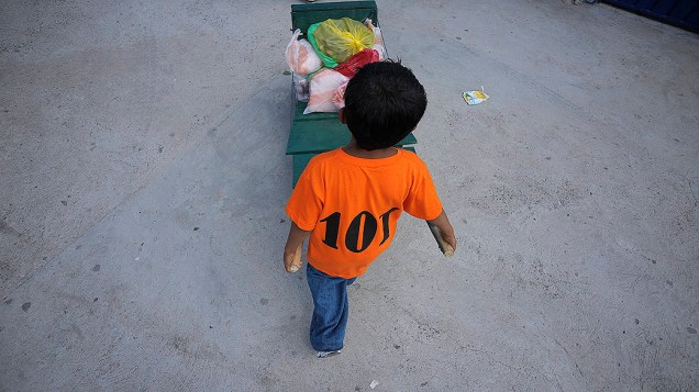 Criança hondurenha de dez anos de idade, transporta mantimentos em um carrinho de mão para um mercado na cidade Tegucigalpa