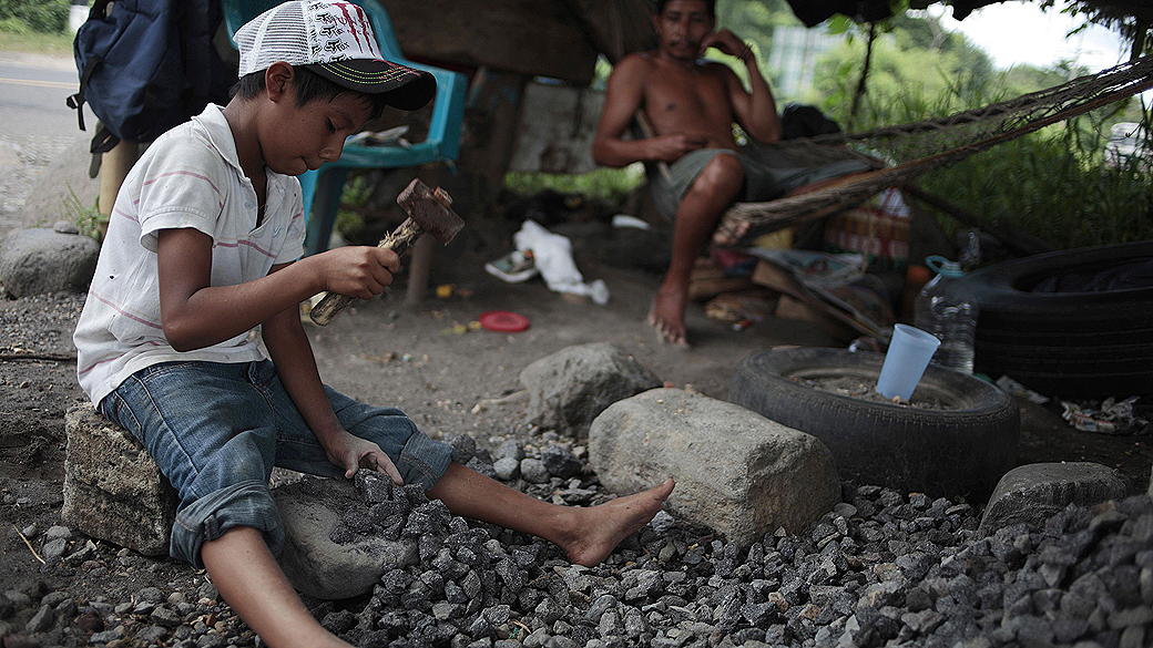 Menino de 9 anos usa martelo para quebrar pedras em estrada para Mazatenango, na Guatemala