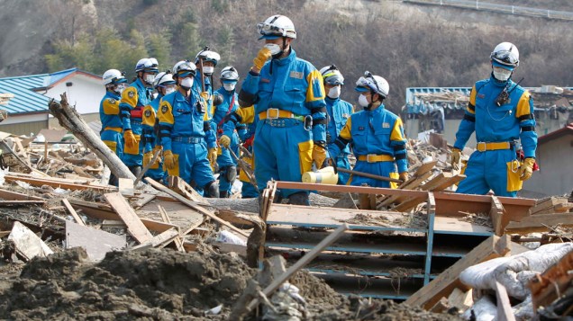 Equipe de resgate japonesa caminha por escombros das casas da cidade de Rikuzentakata em busca de sobreviventes