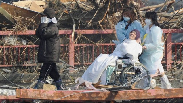 Enfermeiras transportam paciente durante a evacuação de hospital atingido por terremoto, na cidade de Otsuchi, no Japão