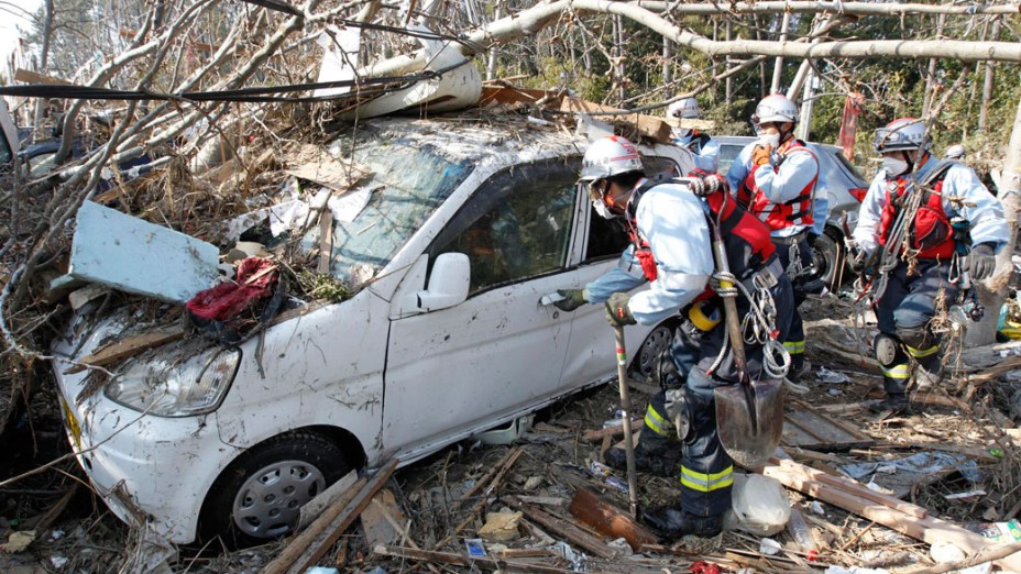 Equipe de resgate japonesa busca sobreviventes dentro de um carro arrastado pelo tsunami