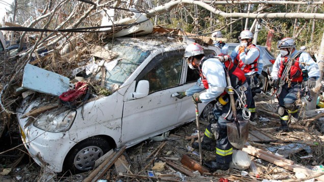 Equipe de resgate japonesa busca sobreviventes dentro de um carro arrastado pelo tsunami