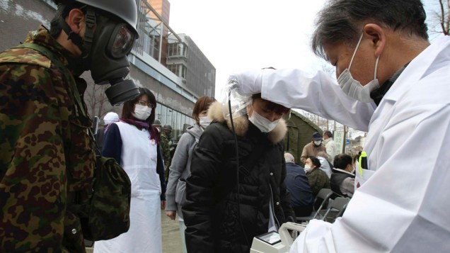 Oficial mede nível de radiação em jovem que evacuou a área perto da usina nuclear de Fukushima, no Japão