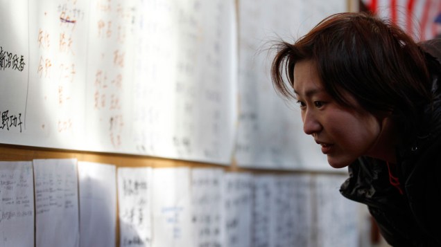 Sobrevivente procura pelo nome de familiares em painel montado na cidade de  Rikuzentakata