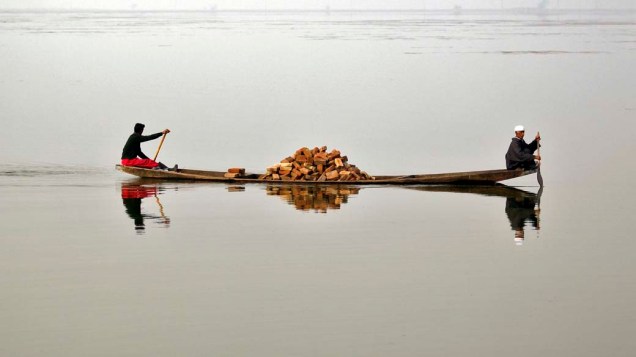 Homens na região da Caxemira indiana carregam tijolos no lago Dal em Srinagar