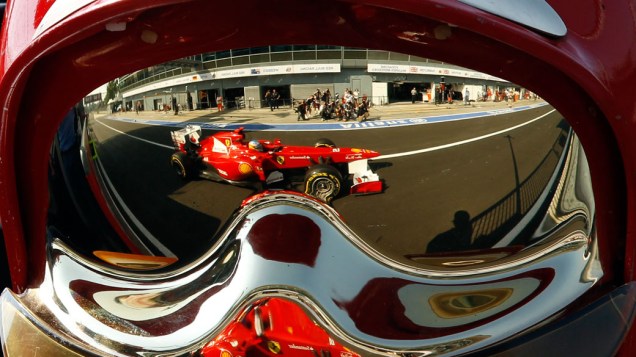 Fernando Alonso, da Ferrari, é visto no reflexo do capacete do mecânico da equipe, durante os treinos para o GP da Itália