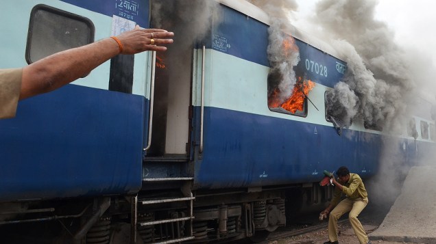 Indiano da equipe de ferrovias do país cobre o rosto ao se aproximar de vagão em chamas em Jodhpur