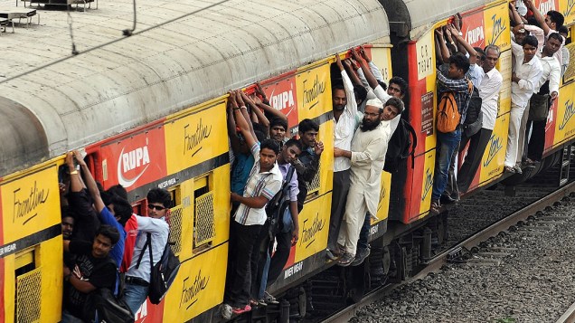 Passageiros se penduram em portas de trem superlotado em Mumbai, na Índia