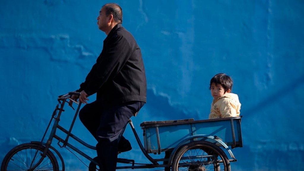 Homem em triciclo leva criança pelas ruas de Pequim, na China
