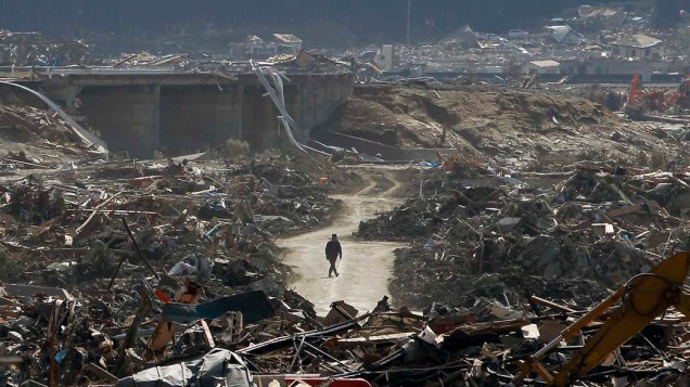 Homem caminha em meio a devastação pelo tsunami em Rikuzentakata, Japão