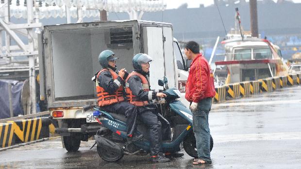 Membros da guarda costeira de Taiwan orientam os pescadores a deixarem o local antes do tsunami atingir a costa da ilha
