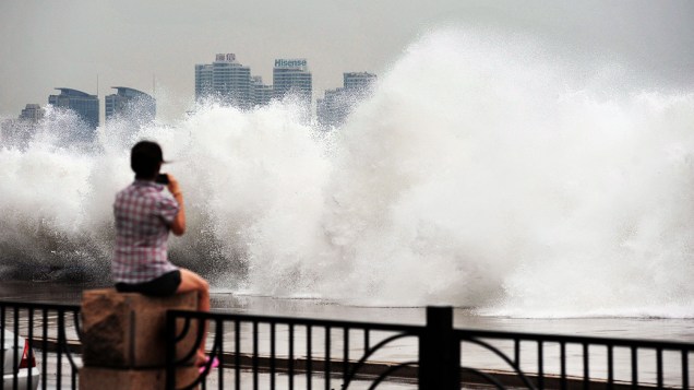 Jovem observa onda gigante em Qingdao, na China, provocada pela passagem do tufão Bolaven pela região