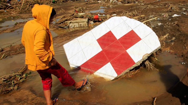 Mulher anda entre destroços da Cruz Vermelha, em Cagayn de Oro, após a região ser atingida por tufão - 18/12/2011