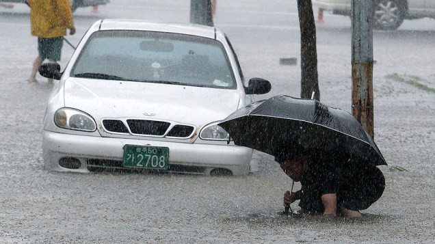 Morador tenta atravessar rua alagada após a passagem do tufão Tembim, na Coreia do Sul
