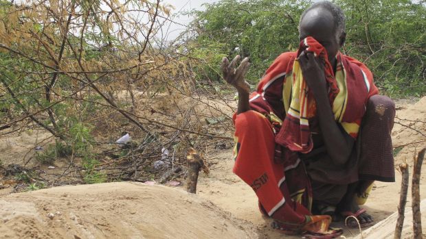 Pai chora diante do túmulo de seu filho na Somália; a cada três meses, 1 em 10 crianças morre de fome no país