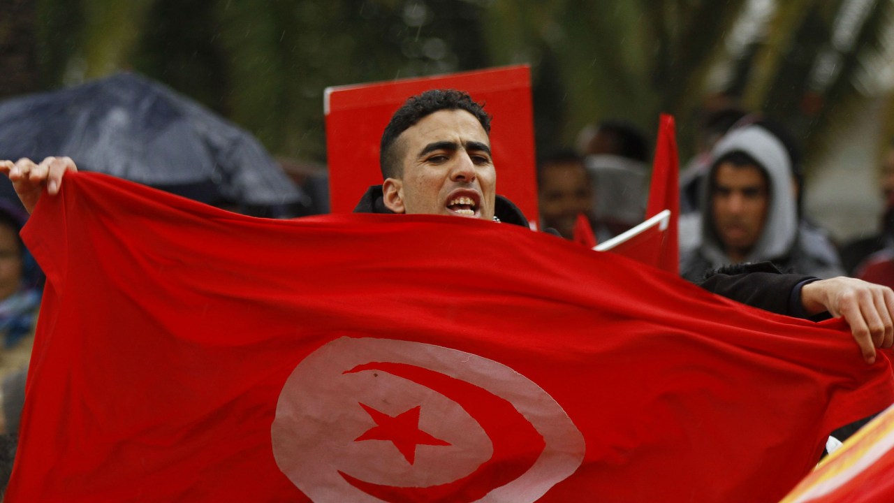 Manifestante segura a bandeira da Tunísia