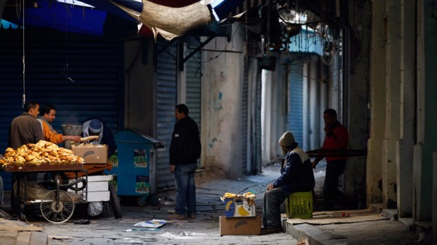 Vendedores ambulantes tentam vender alimento em meio a lojas fechadas e protestos na capital da Tunísia - 13/01/2011