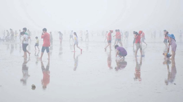 Turistas aproveitam praia em dia nublado na cidade chinesa de Qingdao