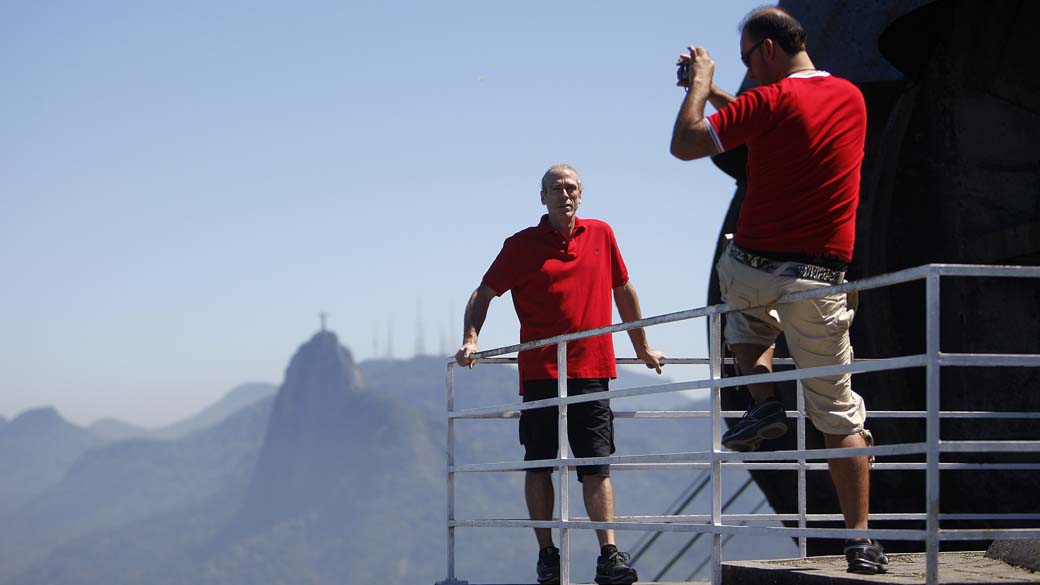 Turistas fotografam, com Cristo Redentor ao fundo, no Rio de Janeiro