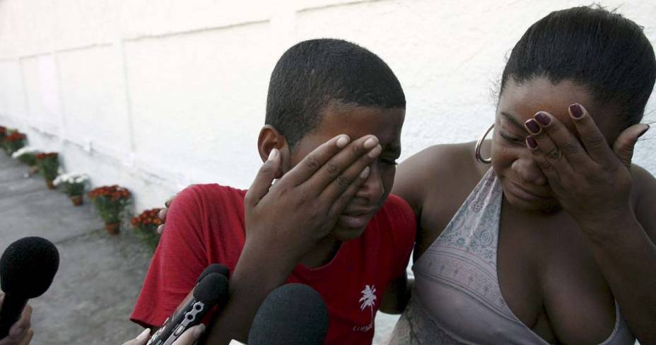 Familiares das vítimas do massacre em Realengo choram após colocarem flores na fachada da Escola Municipal Tasso da Silveira, Realengo, Rio de Janeiro