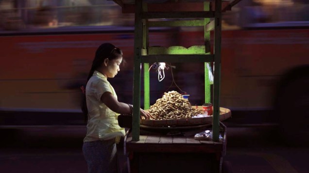 Mulher vende amendoins em rua do centro de Yangun, Mianmar
