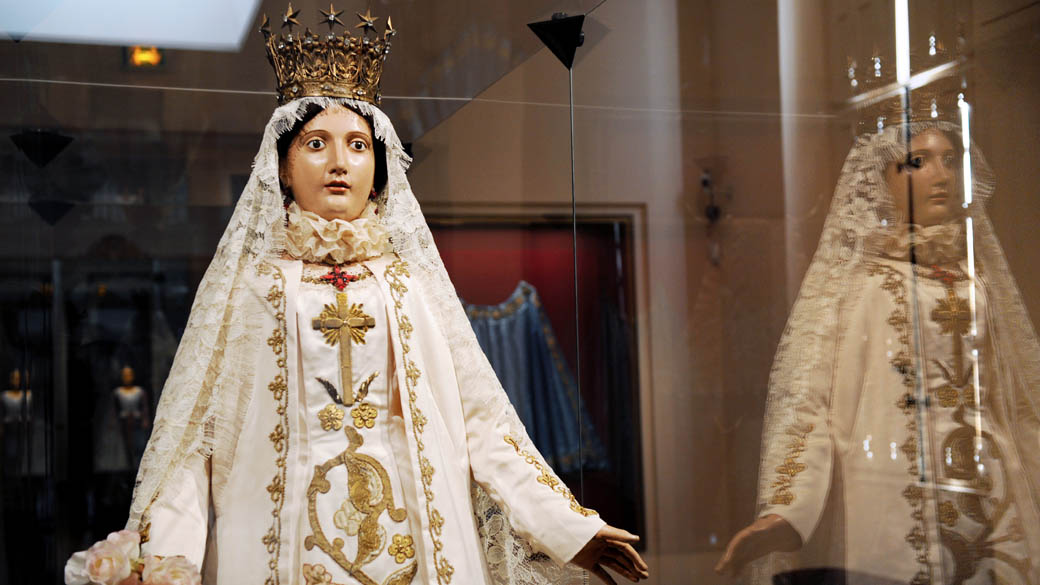 Estátua da Virgem Maria em exposição inspirada em vestimentas da santa, transformada em ícone da moda no museu de tecidos em Lyon, França