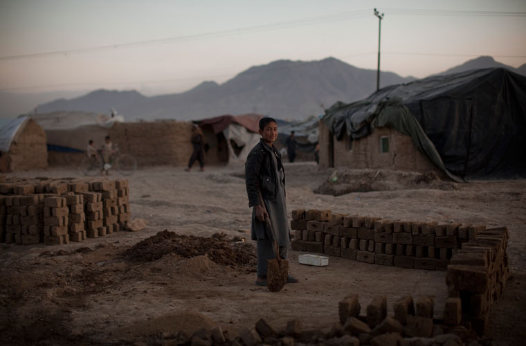 Menino fabrica tijolos em um campo de refugiados em Cabul.