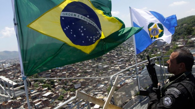 Policiais hasteiam a bandeira do Brasil e a do Estado do Rio de Janeiro no largo dos Coqueiros, no alto do Complexo do Alemão, no Rio de Janeiro - 28/11/2010