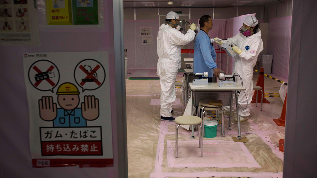 Trabalhador é examinado após entrar no centro de operações de emergência, do complexo nuclear de Fukushima, no Japão