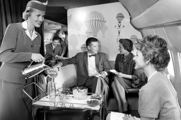 O conforto de uma sala de estar em voo da companhia Pan Am, com bebidas e petiscos