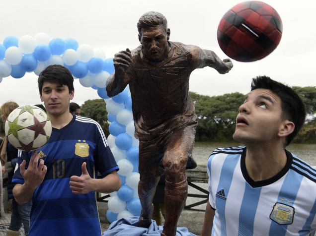 Fãs de Lionel Messi fazem malabarismo com a bola em frente a uma escultura do craque da seleção argentina inaugurada no Paseo de la Gloria, em Buenos Aires - 28/06/2016
