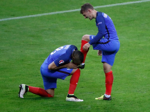 O francês Dimitri Payet beija a chuteira do companheiro Antoine Griezmann na vitória sobre a Islândia