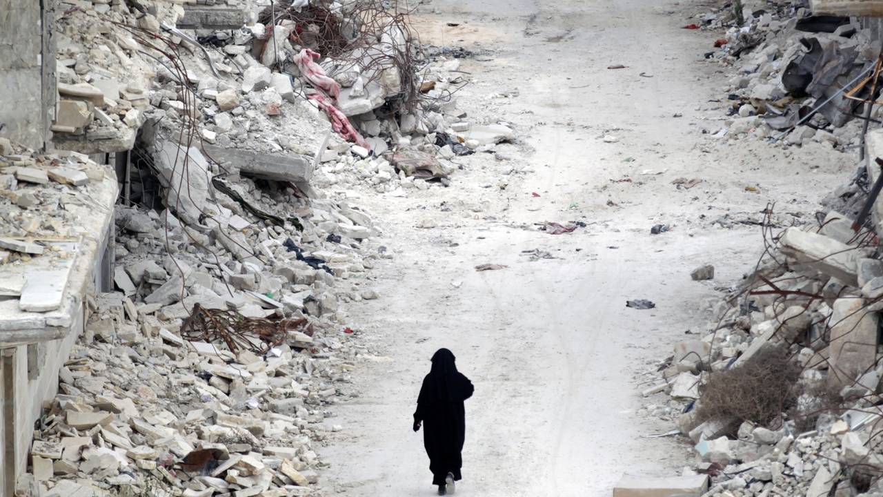 Mulher caminha por entre escombros na província de Idlib, na Síria
