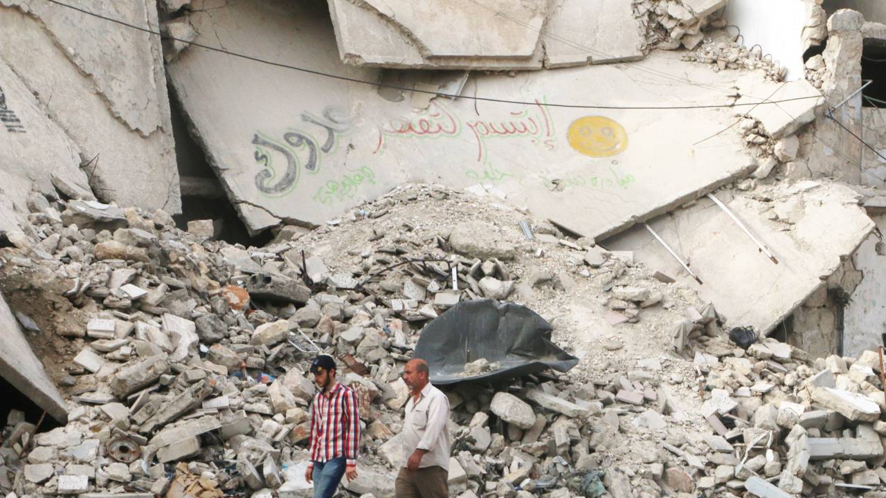 Homens andam próximos à prédio destruído, no distrito de al-Fardous, em Aleppo, norte da Síria - 26/05/2016