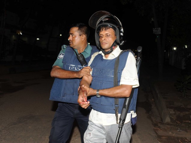 Policial ferido caminha para fora de restaurante que esteve sob ataque de um atirador em Bangladesh - 01/07/2016