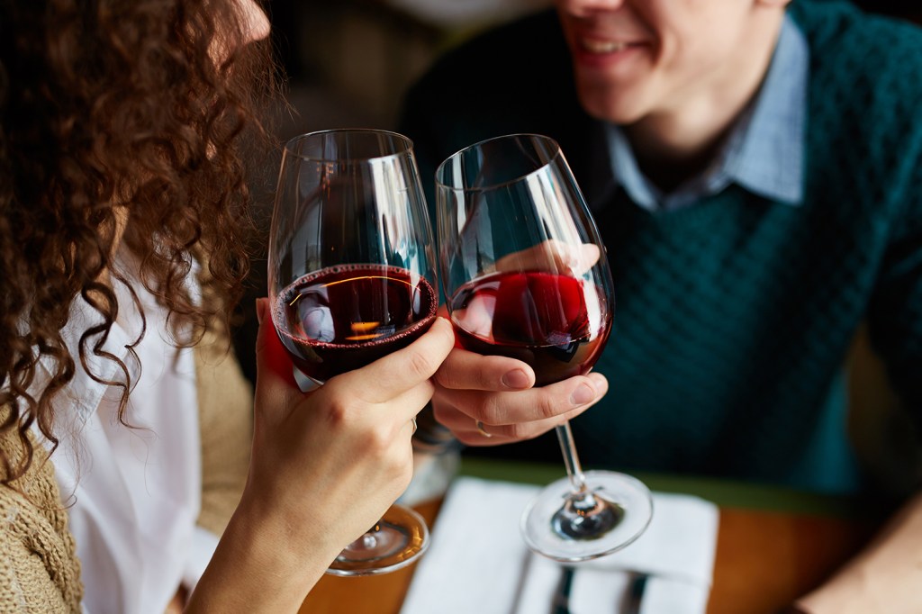 Casal brindando com vinho, em restaurante