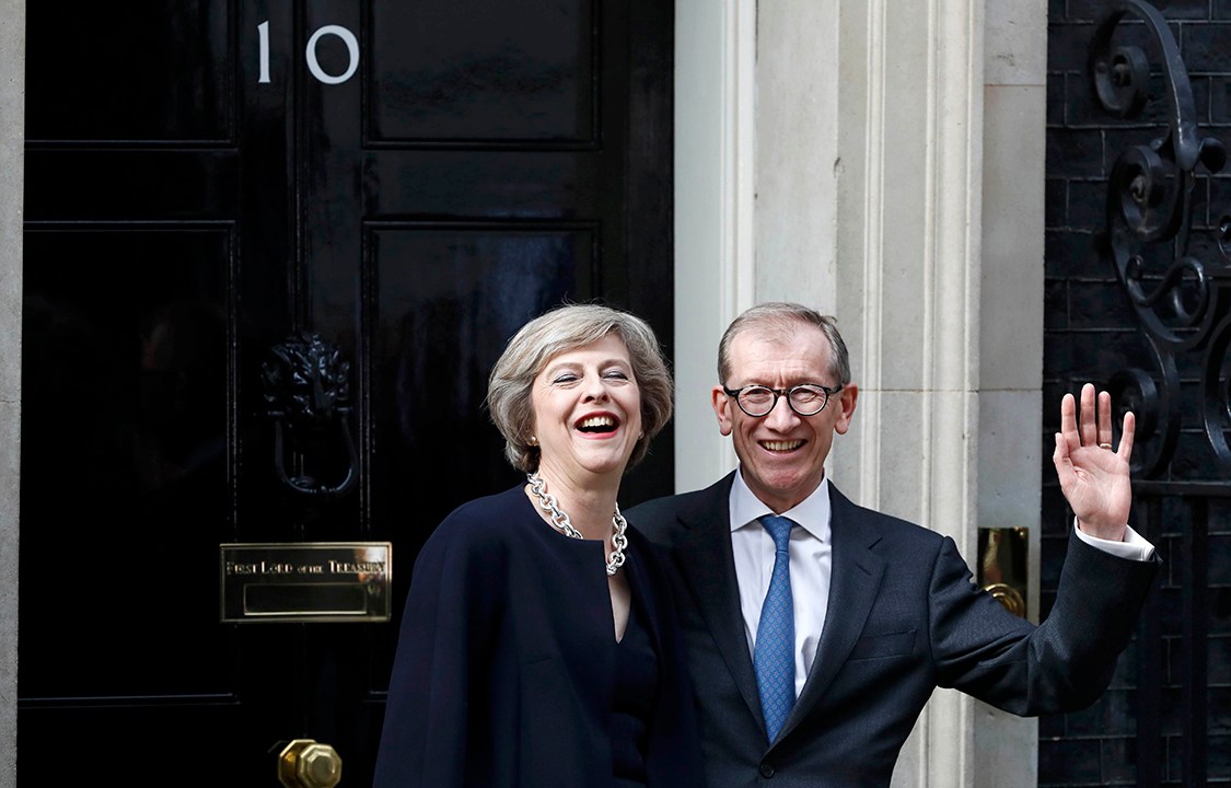 Theresa May, nomeada Primeira-Ministra da Inglaterra, acena para fotógrafos ao lado do marido, Phillip, em frente ao gabinete que ocupará durante seu mandato