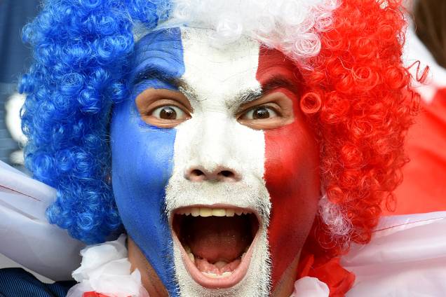 Homem pinta o rosto com as cores da bandeira da França em homenagem ao Dia da Bastilha, dia em que se comemora a queda da Bastilha, estopim da Revolução Francesa de 1789