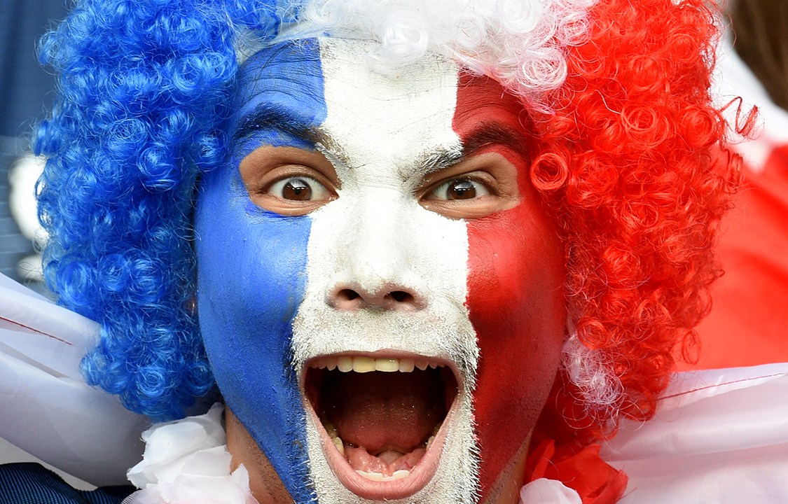 Homem pinta o rosto com as cores da bandeira da França em homenagem ao Dia da Bastilha, dia em que se comemora a queda da Bastilha, estopim da Revolução Francesa de 1789
