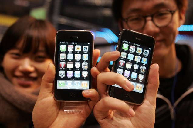 Sul-coreanos mostram o iPhone 3Gs que acabaram de comprar após uma longa fila de espera, em 2009