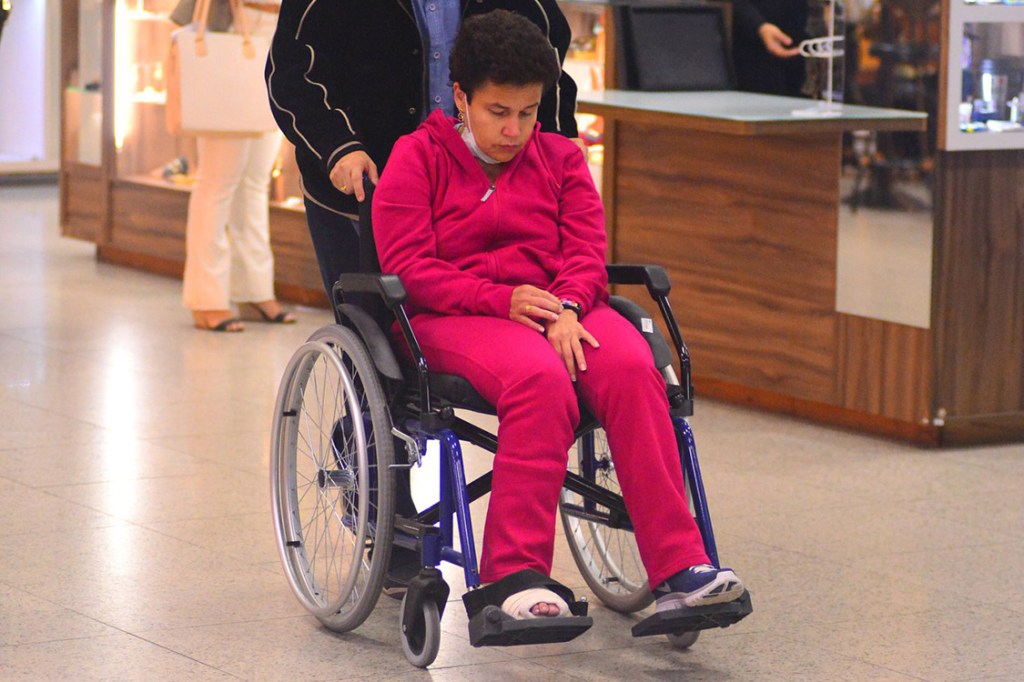 A atriz Cláudia Rodrigues embarca em cadeira de rodas e pé enfaixado no aeroporto Santos Dumont, no Rio