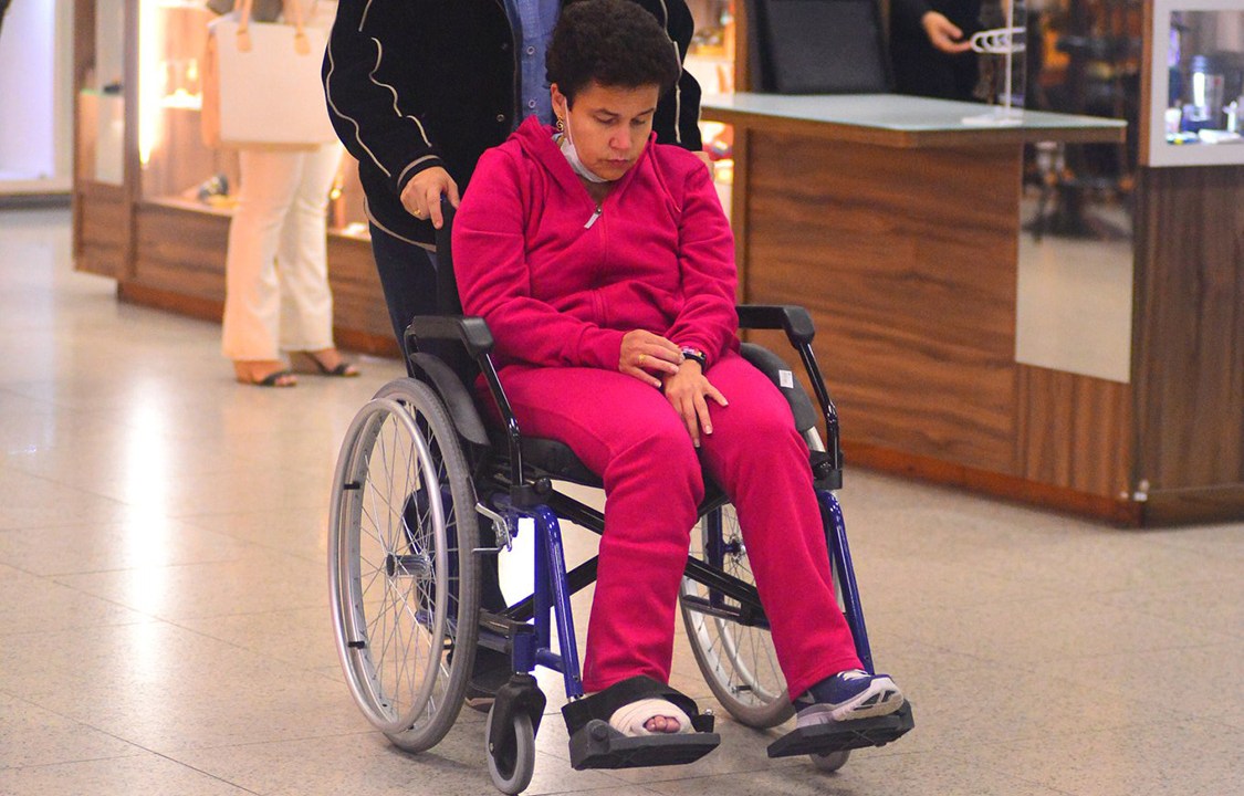 A atriz Cláudia Rodrigues embarca em cadeira de rodas e pé enfaixado no aeroporto Santos Dumont, no Rio
