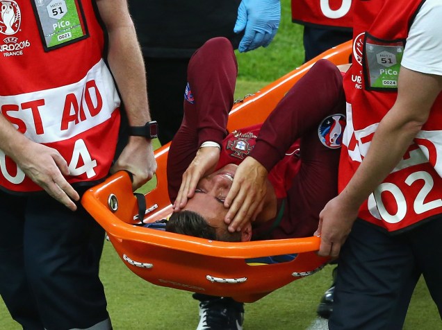 O português Cristiano Ronaldo chora após sofrer lesão e deixar o campo de maca