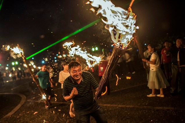 Pessoas participam do Festival da Tocha, em Xichang, na China - 27/07/2016