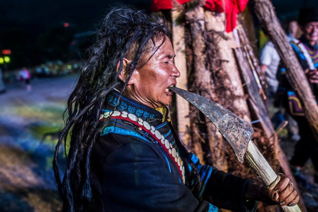 Um xamã (Pessoa considerada influente entre o mundo dos espíritos bons e maus), coloca uma pá quente em sua boca, durante o Festival da Tocha, em Xichang, na China - 27/07/2016